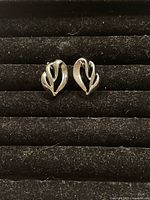 Photo of a pair of vintage clip on earrings showing the front with a silver-tone leaf style design.
