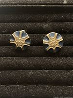 Close-up of the pair of vintage clip-on earrings showing the enamel and gold-tone metal design.