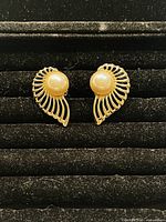 Front view of the vintage gold plated clip on earrings showing pearl center and openwork swirl design.