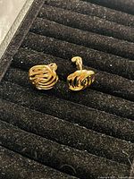 Front view of the pair of gold plated clip-on earrings showing their open twisted ribbon design.