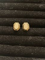 Close-up photo of the pair of vintage clip-on gold plated earrings, showing the octagonal faceted edges and smooth center on black velvet background