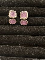 Front view of both clip-on earrings placed on black velvet showing the lavender enamel and silver-tone rope border.