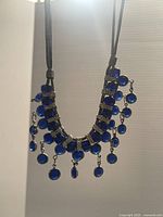 Full view of vintage necklace with blue glass gems and dangling drops.