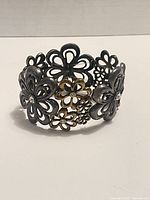 Front view of vintage filigrana bracelet showing multiple floral openwork designs in silver and gold tones with small clear stones.