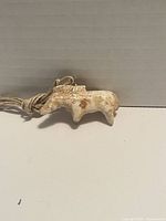 Front view of the vintage carved bone horse pendant showing the string loop and aged cream-colored bone with patina.