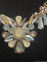Close-up of central flower-shaped cluster featuring marquise, round, teardrop, and circular rhinestones with opalescent and clear qualities.