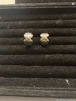 Front view of vintage two-tone earrings showing the silver and gold plated design with an X crossing pattern on textured fan background.