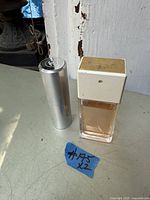 Two Chanel perfume bottles on a surface, one rectangular with a white and gold cap, the other metallic cylindrical bottle.