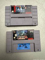 Photo showing two SNES game cartridges, John Madden Football and P.T.O. II, placed one above the other on a light surface.