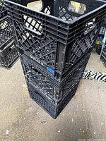 Stack of 3 black plastic milk crates with open lattice sides and handles, showing typical wear.