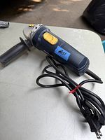 Photo showing the full angle grinder with power cord and yellow power switch.