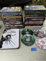 Two stacks of DVD movie cases including titles like Scooby-Doo, Marilyn Manson Dead Alive, Color Out of Space, Zombie Infection, A Darker Reality and Twilight Zone, along with visible discs for Twilight Zone and My Little Pony.