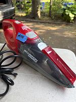 Red Dirt Devil Scorpion Max Power handheld vacuum with power cord, showing side view and product labels.