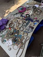 Overall wide view of the jewelry laid out on a table showing assorted items including necklaces, bracelets, rings, and earrings in various materials and colors.