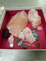 Natural crystal quartz and assorted minerals arranged in a box, highlighting sizes, colors, and textures