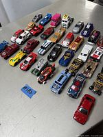 Overview of 30 assorted die cast toy cars, mostly Hot Wheels with some Matchbox, showing various colors and styles on a flat surface.