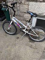 Side view of white Raleigh Dirt Cross DX bicycle showing frame, tires, saddle, and kickstand