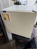 Side view of small off-white mini fridge showing dented and scratched surface.