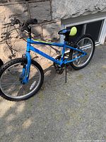 Full side view of the blue Supercycle Charge kids bicycle showing the frame, tires, pedals, and seat.
