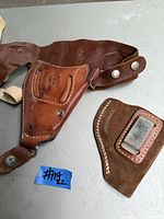 Vintage Bianchi 9R leather upside down shoulder holster with a small Bianchi clip holster placed on a table.