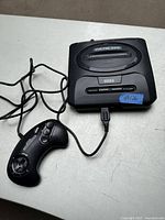 Photo showing Sega Genesis console with wired controller connected, top view
