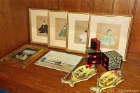 Overview of four framed Japanese silk paintings, two ceramic ladle rests, oil paintings, jewelry box, and Sporting Powder tin on wooden surface