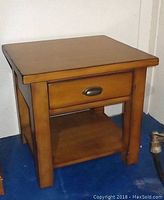 Front view of solid wood Pottery Barn coffee table in cherry finish with drawer and lower shelf.
