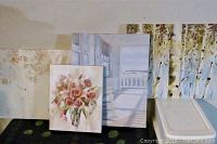Four assorted canvas prints including a floral bouquet, a florals design, scenic porch view, and triptych birch trees, shown side-by-side.