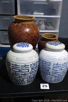 Four ceramic jars displayed together: two white and blue Asian-style ginger jars with lids and two brown ceramic urns with bamboo detailing at the mouth.