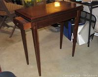 Full view of wooden end table showing drawer partially open and tapered legs.