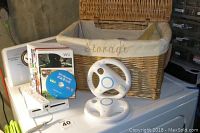 Photo showing Nintendo Wii console, Wii remote controller, assorted Wii games, and a wicker storage basket.