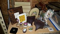 Overall display of assorted decor including frames, bookends, shelves, pill boxes, and horse figurine.