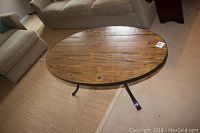 Oval reclaimed wood coffee table with visible wood grain and scratches, metal frame and legs shown from an angled front view.