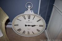 Front view of the oval Kensington wall clock showing crackle paint finish, Roman numerals, and ornamental finial.