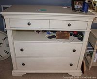 Front view of the whitewash dresser showing four drawers and an open middle storage area with metal round knobs.