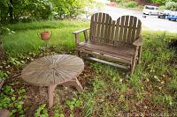 Outdoor Adirondack glider bench and round side table on grass under shade, showing overall condition and placement.