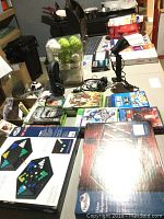 Top-down view of the lot items arranged on a table, showing boxed Pavilion Chinese Checkers and Backgammon games, multiple video game cases, a desktop lamp, and cables.