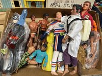 Top-down view of mixed action figures in a cardboard box