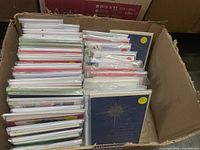 Box containing multiple sets of holiday greeting cards organized vertically inside a cardboard box.