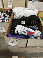 Box of Disney clothing items including pinstripe jacket, colorful T-shirts with Disney and other character prints, folded inside a box.