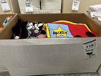 Box containing multiple Disney clothing items including T-shirts with Mickey Mouse graphic prints.