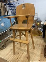 Full view of wood doll high chair showing front, armrests, and animal decal on backrest.