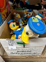 Box filled with multiple vintage Donald Duck toys of varying sizes and designs