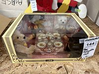 Boxed display with four Steiff bears and miniature tea set, front view through transparent window showing all elements