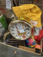 Box containing a large Ronald McDonald clock designed like a pocket watch, yellow McDonald's employee hat and several small items including plaques and balloons.