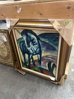 Front angled photo showing the framed painting of a blue horse with a colorful abstract background, frame protected with cardboard corners.