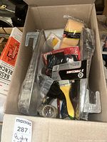 Box with assorted painting supplies including roller covers, brushes, and handles in original packaging and loose