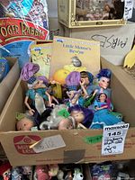 Box containing several Strawberry Shortcake dolls and related children's books packed together.
