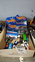 Four Hot Wheels cars in original blister packaging shown together inside a box