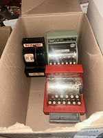 Box containing three toy cash registers, two labeled Tom Thumb and one Benjamin Franklin Saving Bank, showing general worn condition.